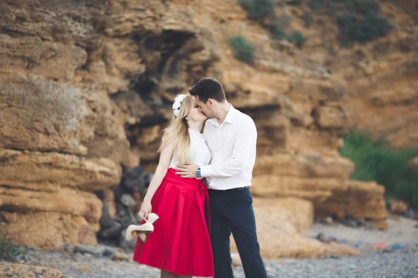 Romántica pareja amorosa caminando por la playa con rocas y piedras —  Fotos de Stock