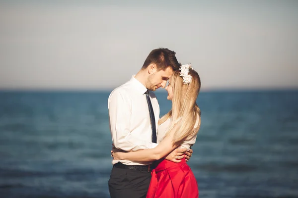 Junges glückliches Paar, das lächelnd am Strand spaziert und sich umschlingt. Liebesgeschichte — Stockfoto