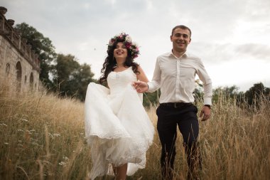 Güzel, romantik bir düğün. Yeni evliler. Eski kalenin yakınlarında sarılıyorlar.