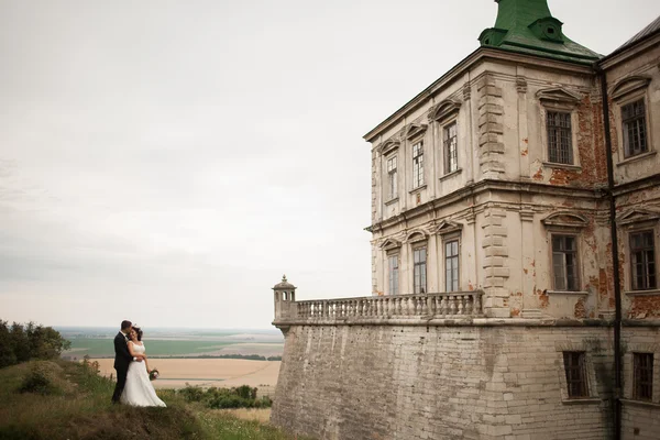 Glückliches Hochzeitspaar umarmt und küsst sich auf alter Burg — Stockfoto