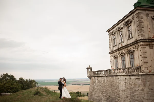 Feliz casamento casal abraçando e beijando no fundo velho castelo — Fotografia de Stock