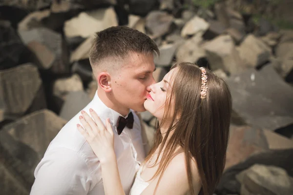 Preciosa novia, novio besándose y abrazándose cerca de los acantilados con impresionantes vistas — Foto de Stock