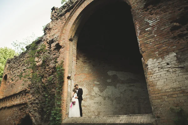 Beautiful fairytale newlywed couple hugging near old medieval castle