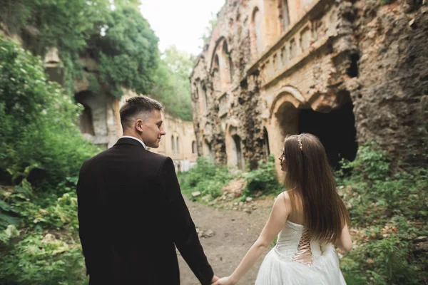 Hermosa pareja de recién casados cuento de hadas abrazándose cerca del antiguo castillo medieval —  Fotos de Stock
