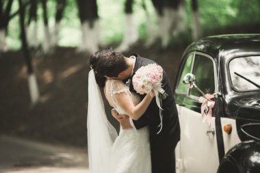 Mutlu yeni evli çift karı şık retro arabanın yakınında öpüşme