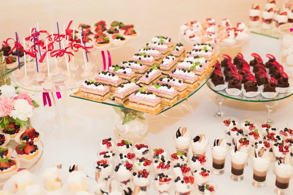 Délicieuse et savoureuse table à dessert avec des petits gâteaux plans à la réception gros plan — Photo