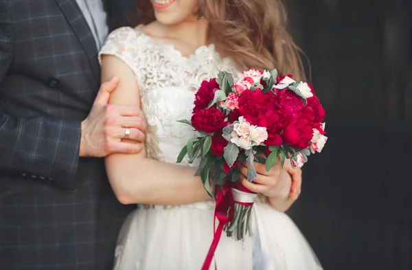 Boda pareja abrazándose, la novia sosteniendo un ramo de flores en su mano, novio abrazando —  Fotos de Stock