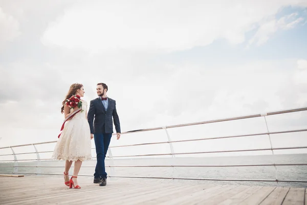 Casamento casal em pé em um cais sobre o mar — Fotografia de Stock