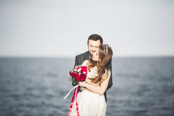 Čerstvě vdaná, Svatební pár, chůze po pláži při západu slunce. — Stock fotografie