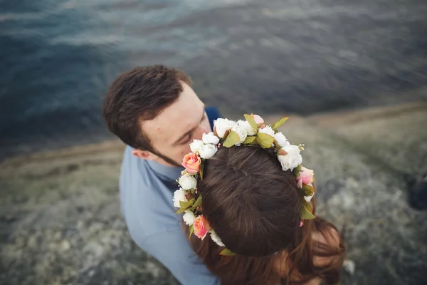 Boda pareja besándose y abrazándose en rocas cerca de mar azul — Foto de Stock