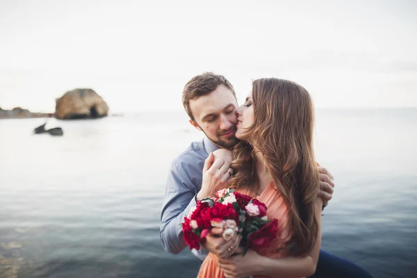 Casamento casal sentado em pedra grande em torno do mar azul — Fotografia de Stock