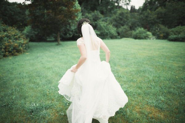 Beautiful wedding bride running in the garden.