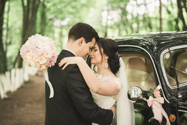 Glückliches Brautpaar, Mann und Frau küssen sich in der Nähe von stylischem Retro-Auto — Stockfoto