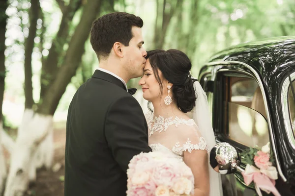 幸せな新婚者のカップル、男と妻のスタイリッシュなレトロな車の近くにキス — ストック写真