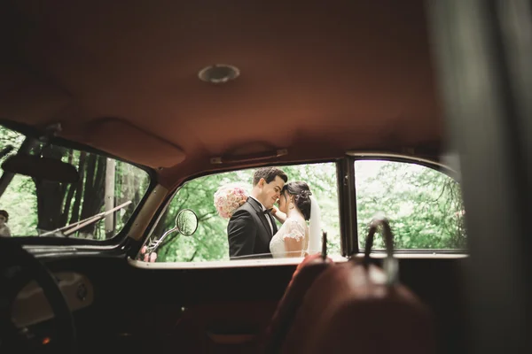 Felice coppia di sposi, uomo e moglie baciare vicino elegante auto retrò — Foto Stock