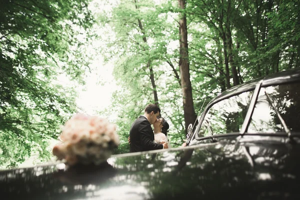 Felice coppia di sposi, uomo e moglie baciare vicino elegante auto retrò — Foto Stock