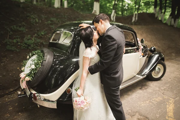 Schönes Hochzeitspaar posiert in der Nähe von herrlichem Retro-Auto — Stockfoto