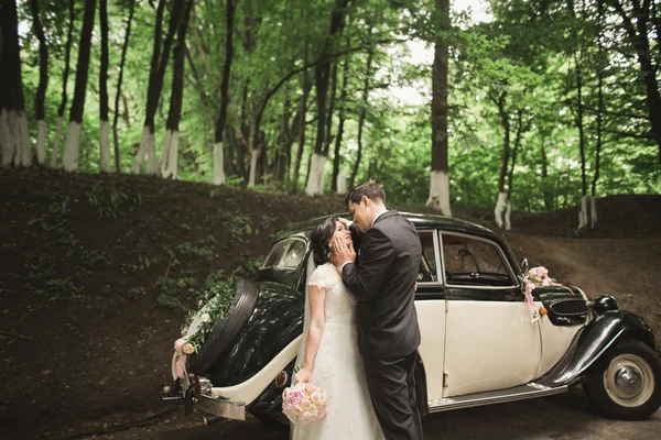 Schönes Hochzeitspaar posiert in der Nähe von herrlichem Retro-Auto — Stockfoto