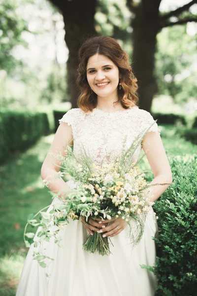 La novia sosteniendo ramo de flores en el parque. Boda — Foto de Stock