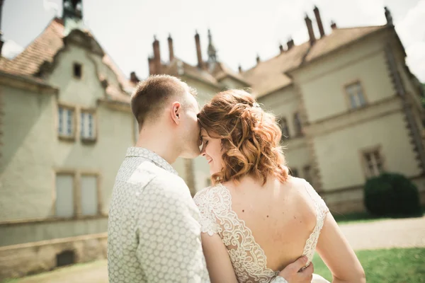 Feliz casamento casal abraçando e sorrindo uns aos outros no fundo velho castelo — Fotografia de Stock