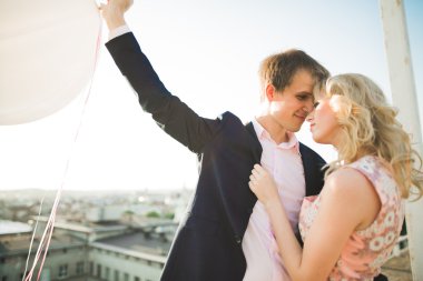 Çatıda mükemmel şehir manzaralı elele ve sarılma poz aşık genç bir çift. Güzel gün batımı