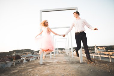 Sevgi dolu çift atlama ve eski şehir'in backgrounf ile çatı üzerinde gülümseyen