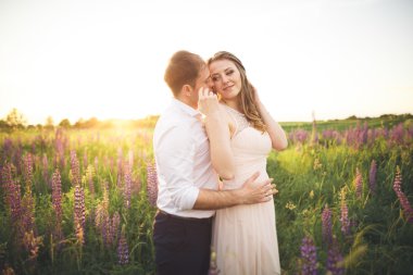 Gelin ve damat, çiçekler, güzel bir alanda gün batımında rissing romantik evli çift