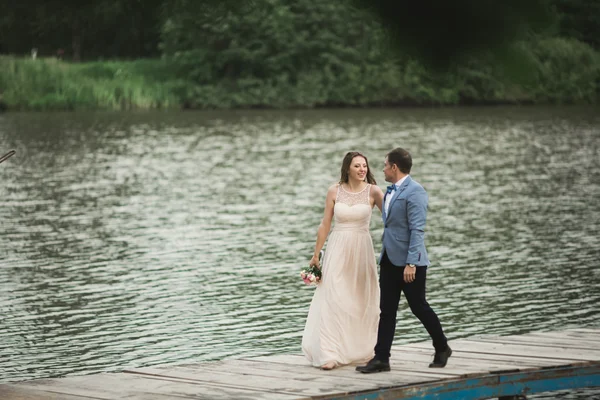 Bruiloft paar, bruid, bruidegom lopen en poseren op pier — Stockfoto