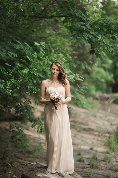 美女名车年轻新娘大礼服站河边，山是在背景上 — 图库照片
