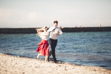 Genç mutlu çift holding birbirlerini etrafında gülümseyen Sahilde yürüyüş. Aşk hikayesi