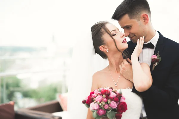 Hermosa pareja, novia y novio posando en el balcón con el fondo de la ciudad vieja — Foto de Stock