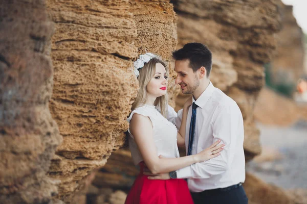 Romántica pareja amorosa caminando por la playa con rocas y piedras — Foto de Stock