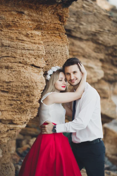 Romantic loving couple walking on the beach with rocks and stones — Stock Photo, Image