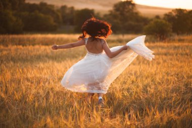 Mutlu, güzel, genç gelin gün batımında bir çayırda.