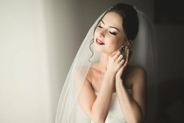 Hermosa novia joven con maquillaje y peinado en el dormitorio, mujer recién casada preparación final para la boda. Chica feliz esperando novio. Retrato de enfoque suave —  Fotos de Stock