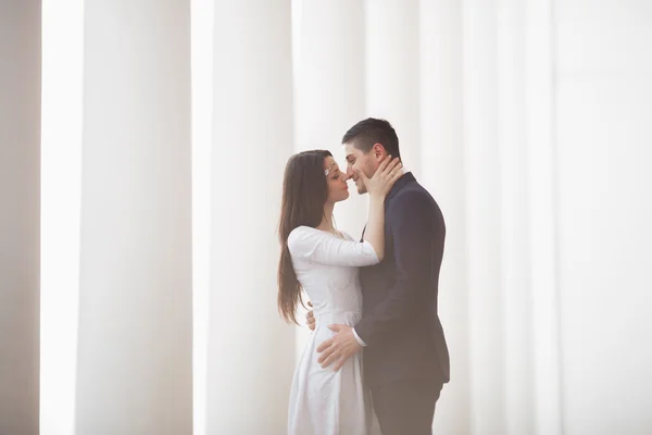 Hermosa pareja, novia y novio posando cerca de gran columna blanca —  Fotos de Stock