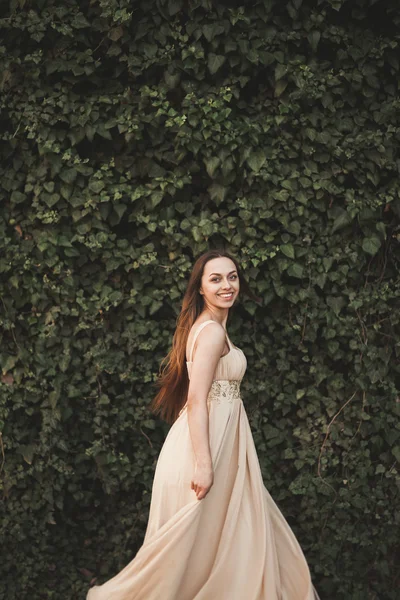 Hermosa chica, modelo cerca de la pared de hojas y arbustos en el parque —  Fotos de Stock