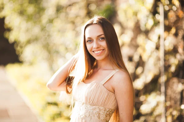 Jovem atraente com vestido longo desfrutando de seu tempo fora no parque por do sol fundo — Fotografia de Stock