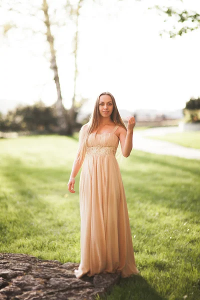 Aantrekkelijke jonge vrouw met lange jurk genieten van haar tijd buiten in park zonsondergang achtergrond — Stockfoto