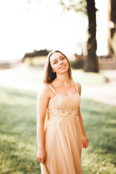 Attraente giovane donna con abito lungo godendo il suo tempo fuori nel parco sfondo tramonto — Foto Stock