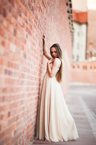 Belle fille sexy avec des cheveux longs et robe forme parfaite corps bronzé posant près du mur — Photo