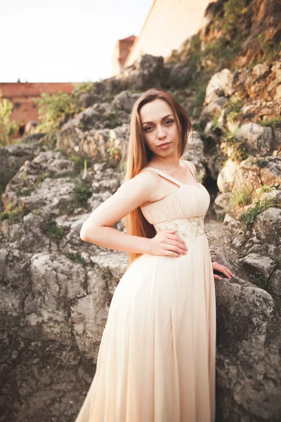 Привлекательная молодая женщина в длинном платье стоит на скалах — стоковое фото