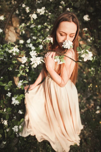 Młoda piękna dziewczyna w długiej sukni i Wieniec kwiatów, w pobliżu ogrodu krzew bzu — Zdjęcie stockowe
