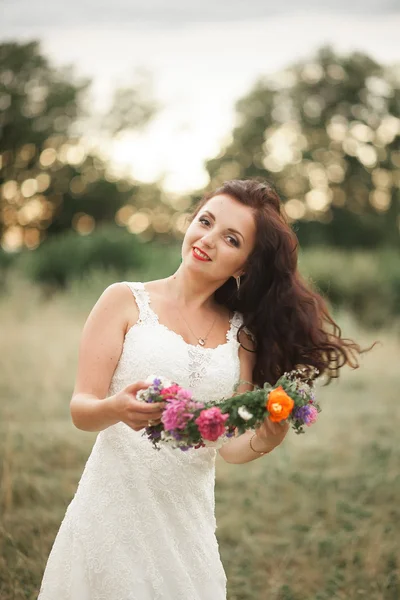 Noiva. Mulher loira jovem bonita no parque com coroa de flores e buquê em um dia quente de verão — Fotografia de Stock