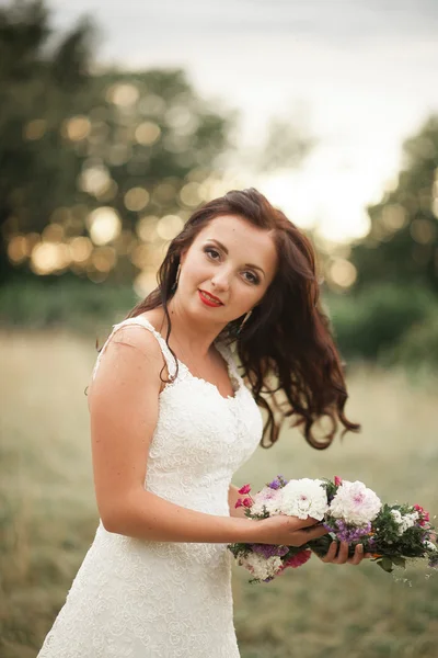 Braut. schöne junge blonde Frau im Park mit Blumenkranz und Blumenstrauß an einem warmen Sommertag — Stockfoto