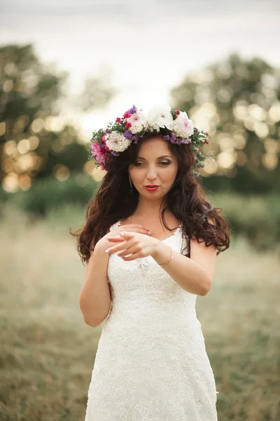 Noiva. Mulher loira jovem bonita no parque com coroa de flores e buquê em um dia quente de verão — Fotografia de Stock