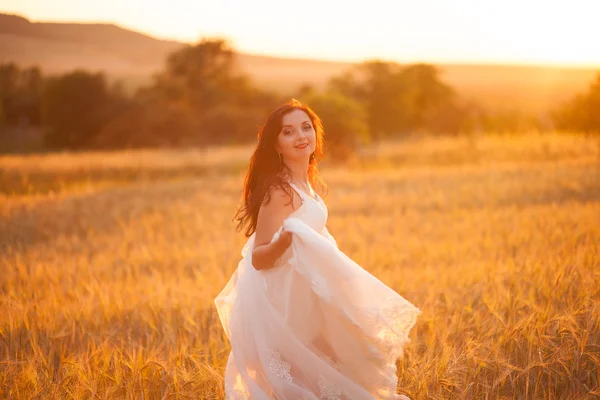 Feliz bela noiva jovem lá fora em um prado de verão no pôr do sol — Fotografia de Stock