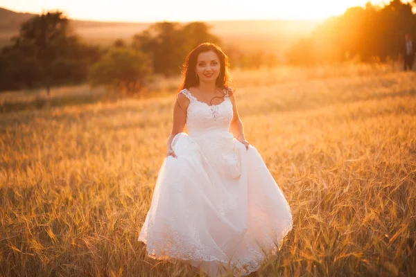 Joyeux beau jeune mariée dehors sur une prairie d'été au coucher du soleil — Photo