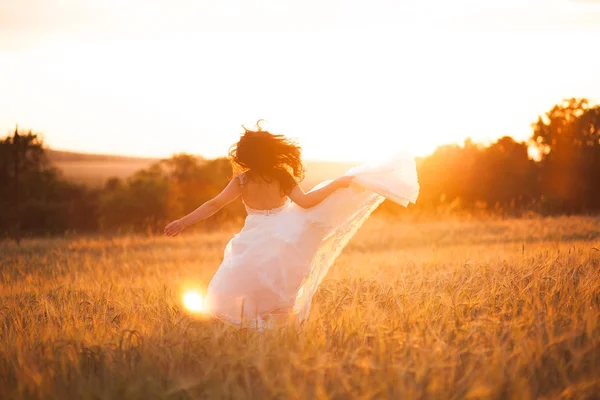 Feliz bela noiva jovem lá fora em um prado de verão no pôr do sol — Fotografia de Stock