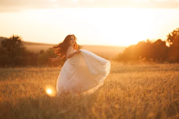 Joyeux beau jeune mariée dehors sur une prairie d'été au coucher du soleil — Photo